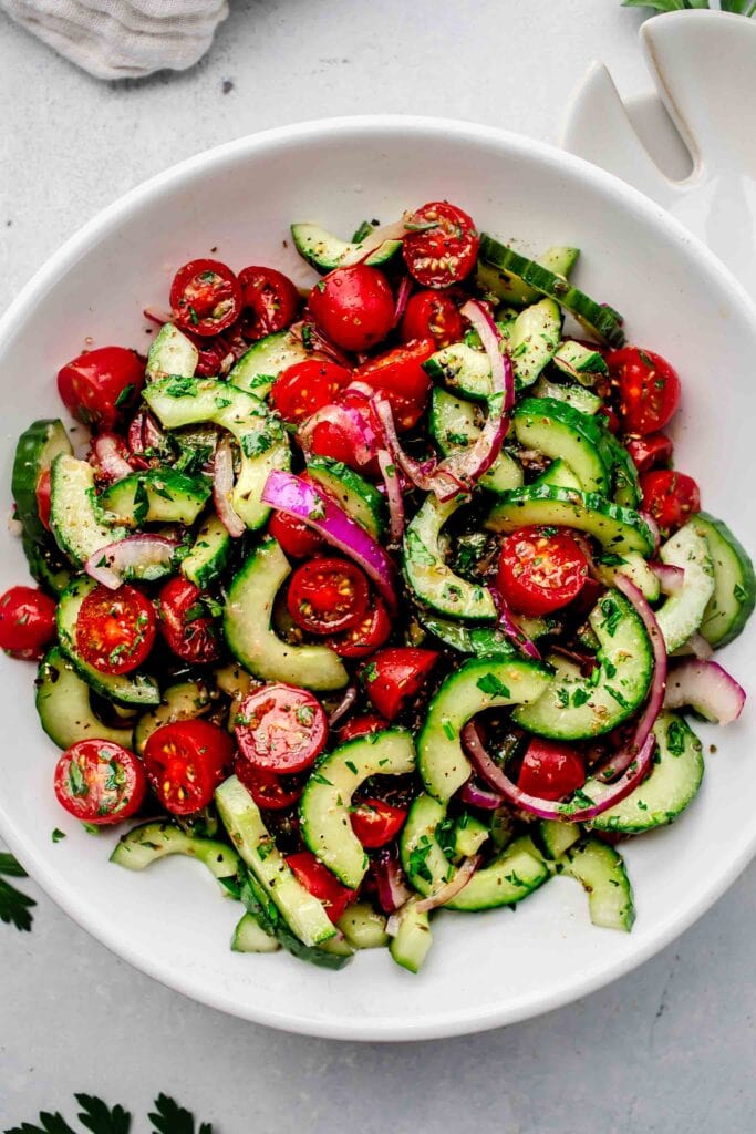 Tomato cucumber salad in white serving bowl. 