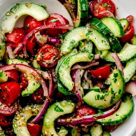 Serving spoon in bowl of tomato cucumber salad.