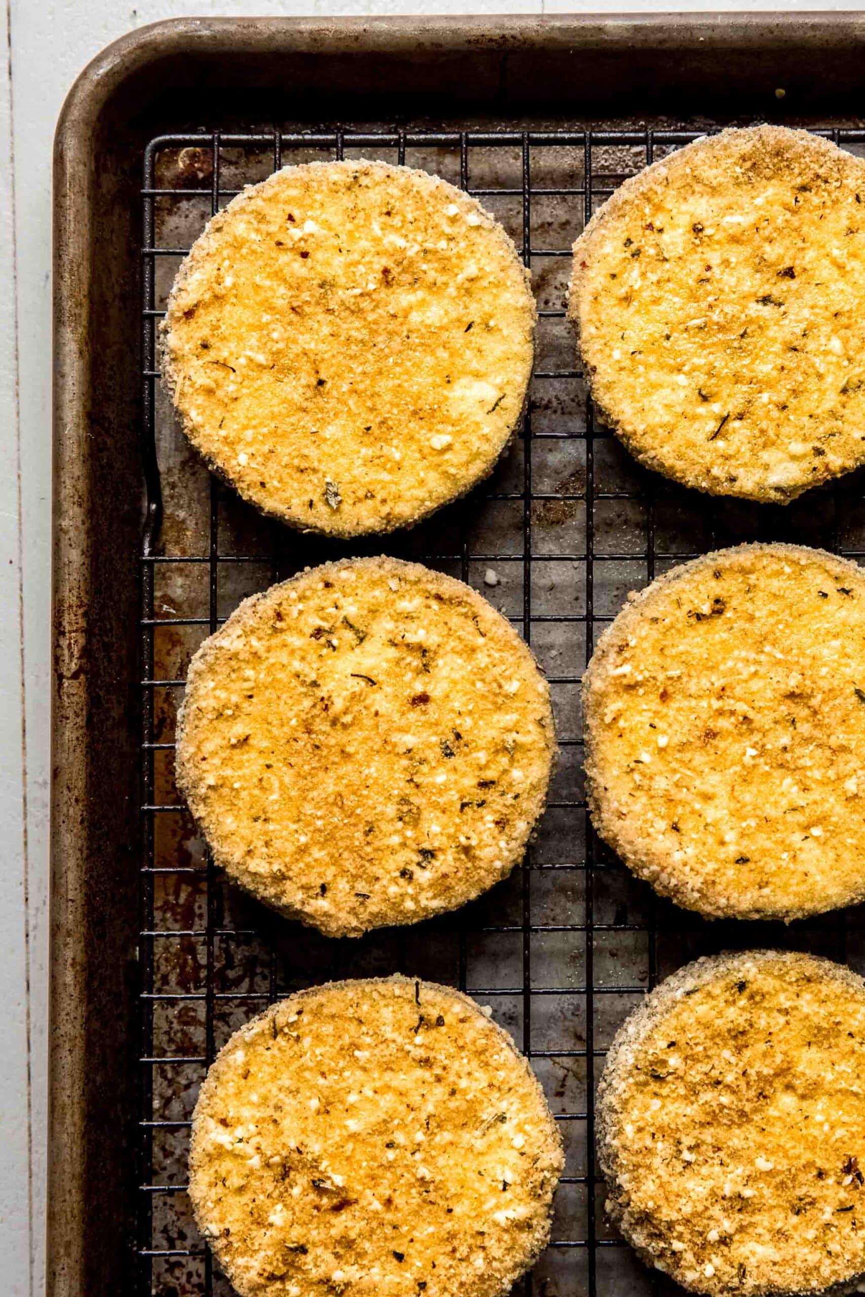 Breaded eggplant slices on tray. 