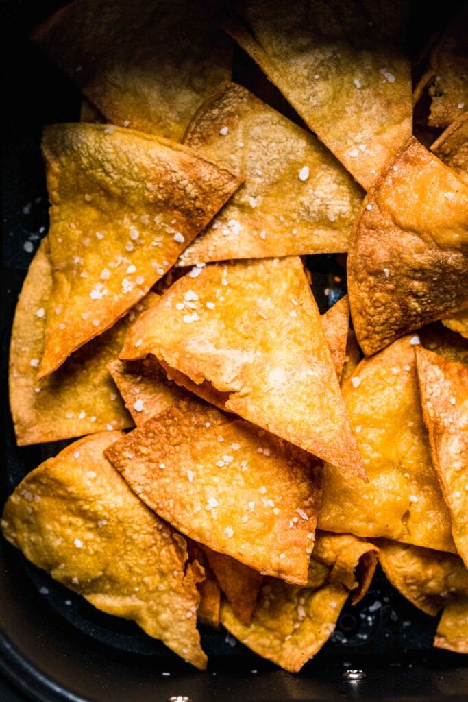 Extreme close up of tortilla chips in air fryer basket.