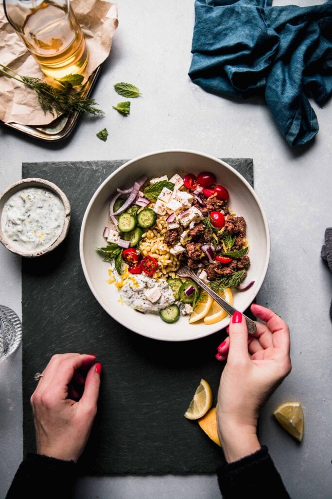 Hand reaching for orzo bowl. 