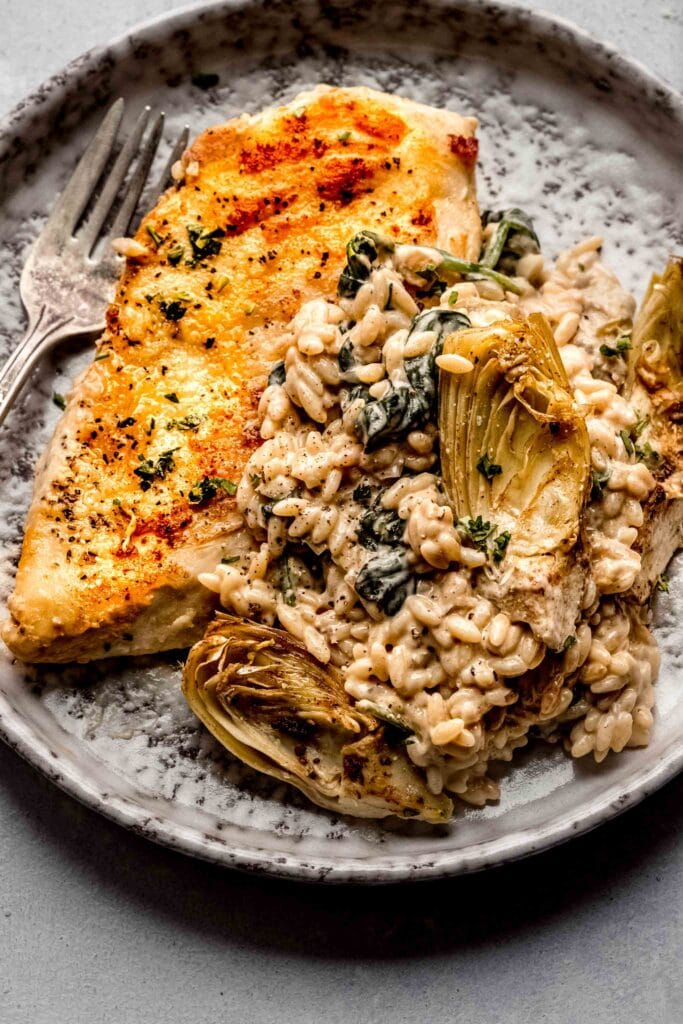 Chicken and orzo on grey plate with fork. 