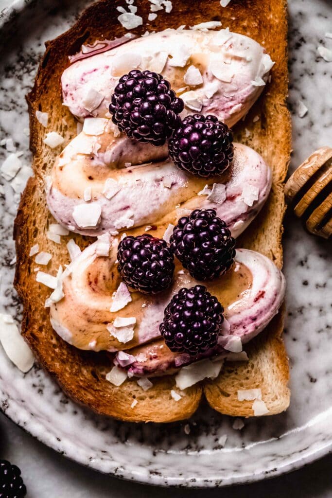 Overhead close up of ricotta toast next to honey wand.