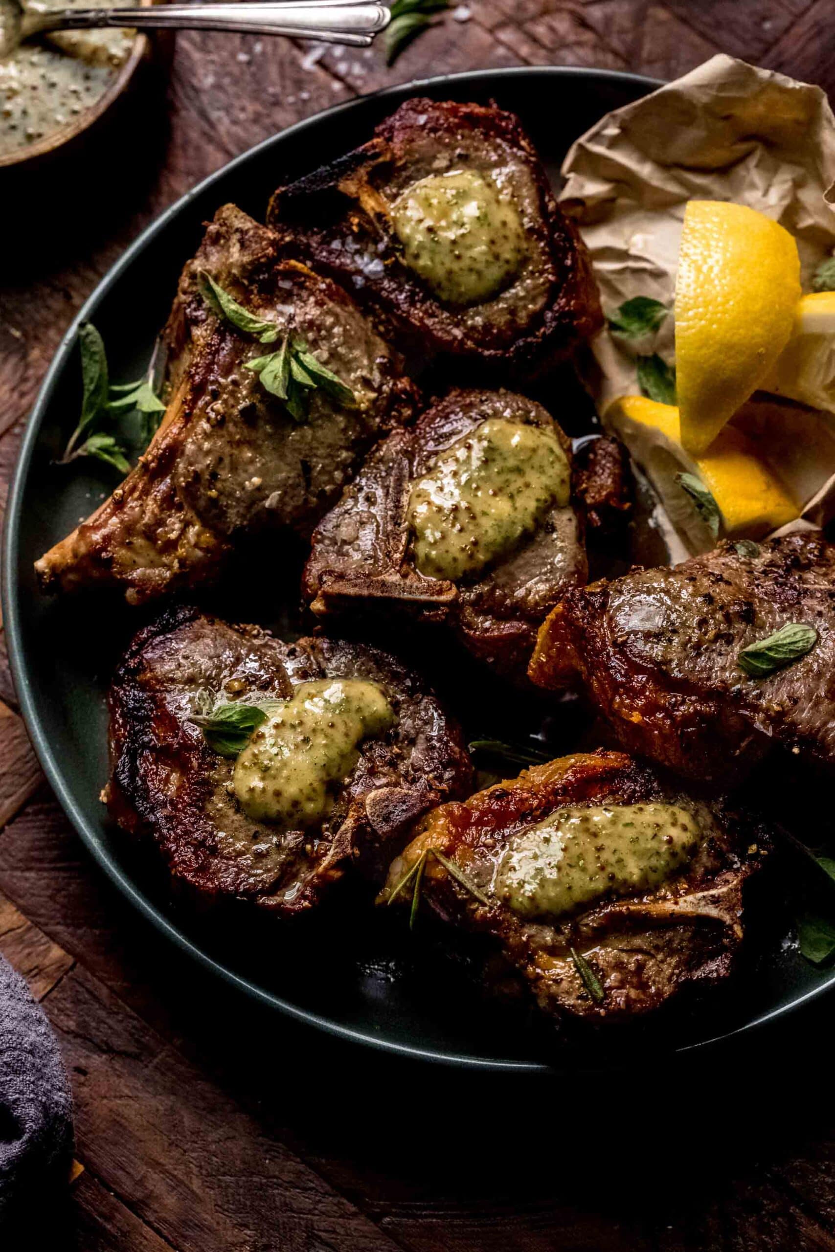 Lamb chops on plate with dollops of mint mustard sauce on top of them.