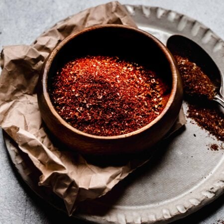 Side view of chili seasoning in small wooden bowl with spoon.