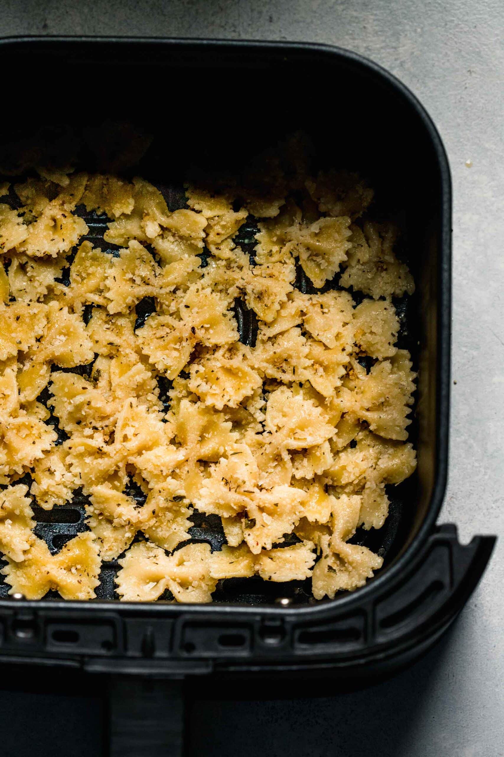 Uncooked pasta chips in air fryer basket. 