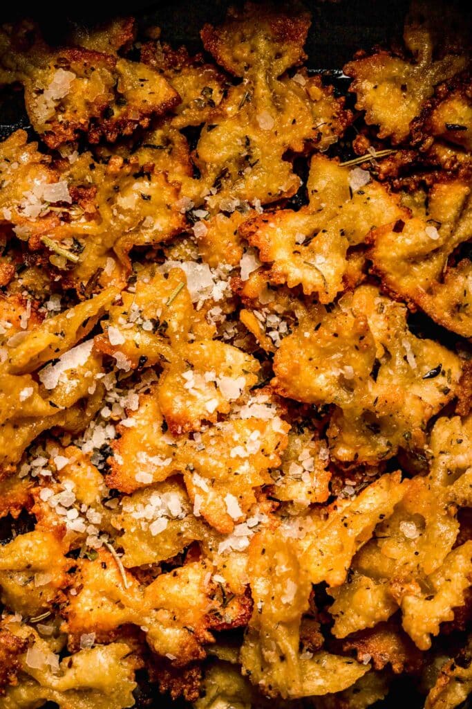Overhead close up of pasta chips sprinkled with parmesan. 