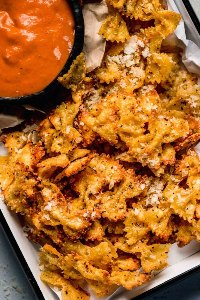 Pasta chips on plate with small bowl of dipping sauce.