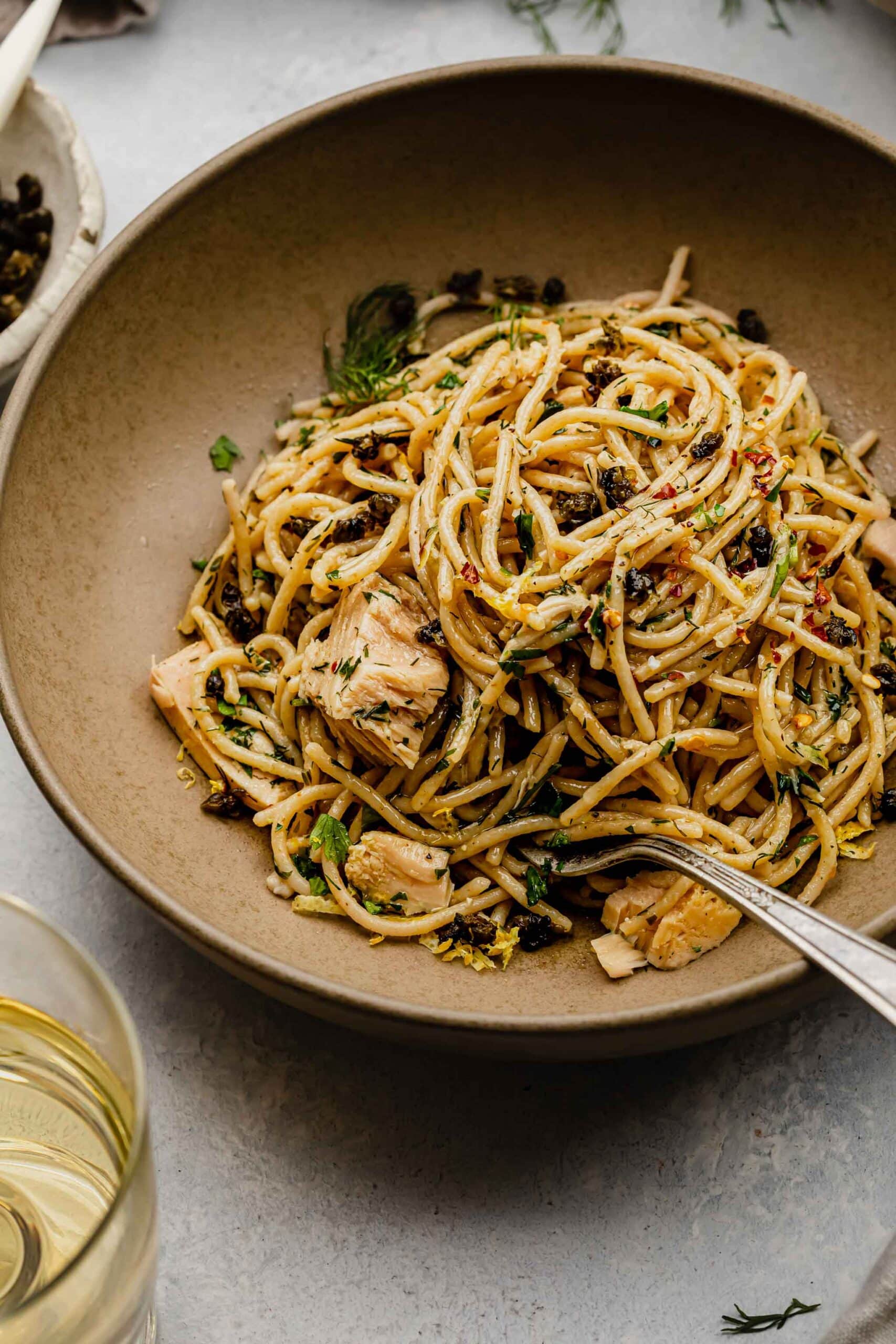 Side view of tuna pasta in brown bowl with fork.