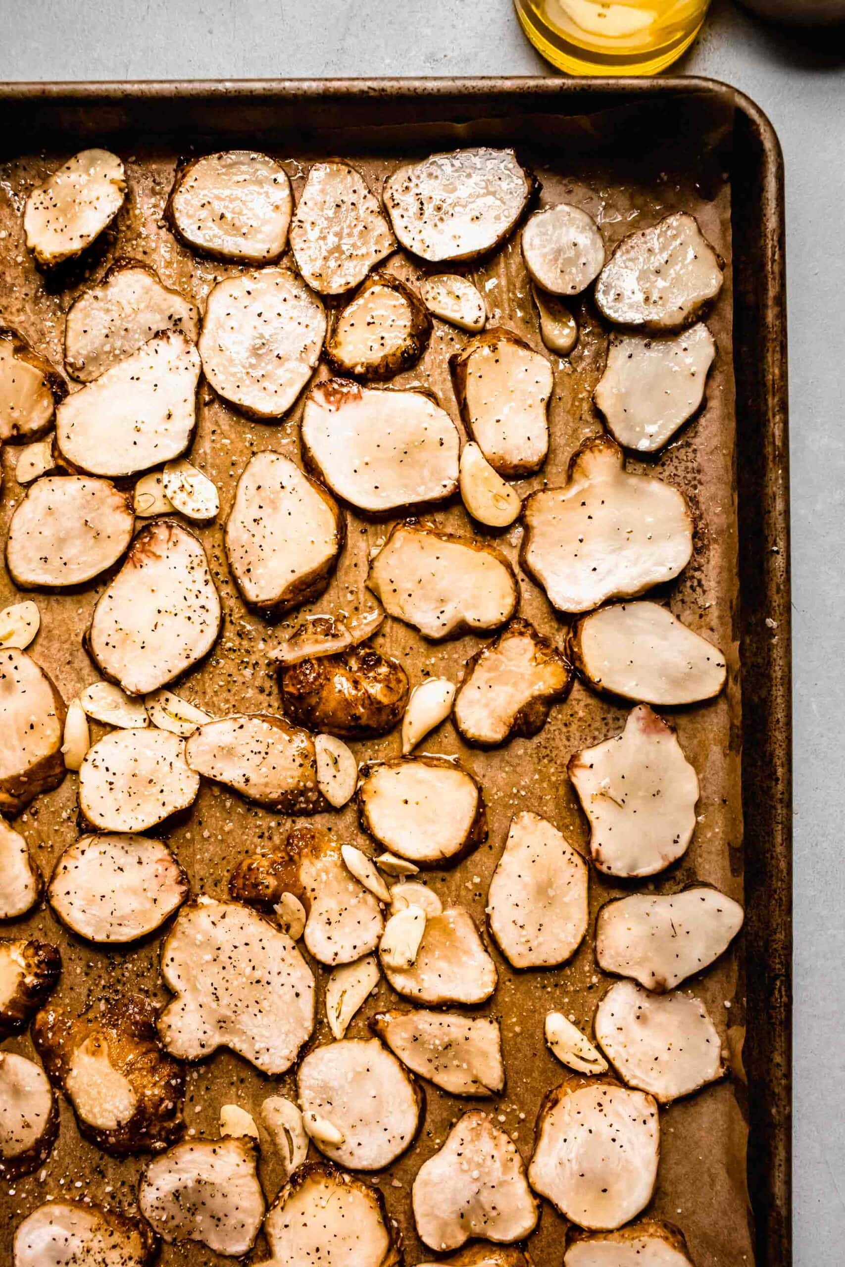 Uncooked sliced sunchokes on baking sheet. 