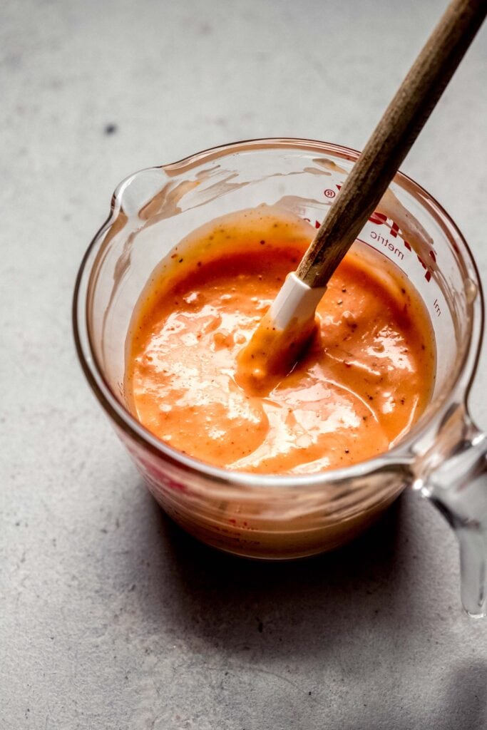 Sauce in mixing jar with spatula. 