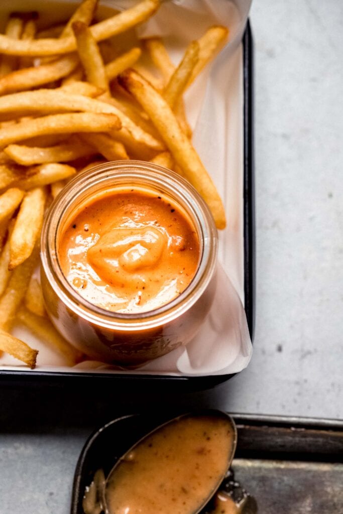 Tray of fries with jar of boom boom sauce.