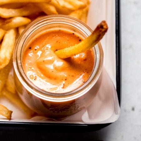 Boom boom sauce in small jar with fry dipping into it.
