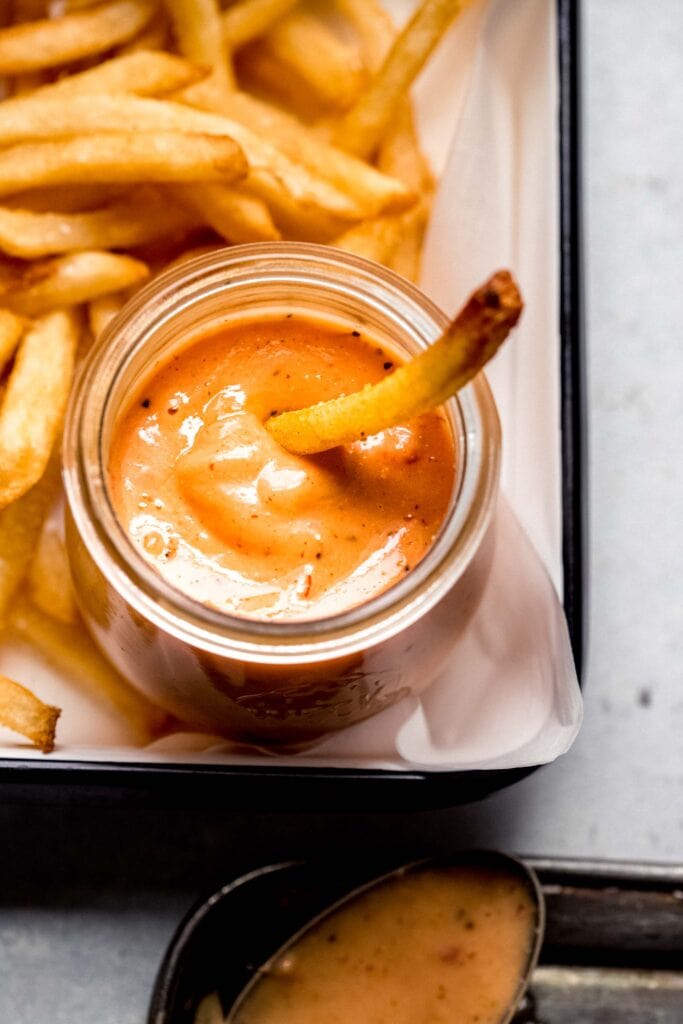 Boom boom sauce in small jar with fry dipping into it.