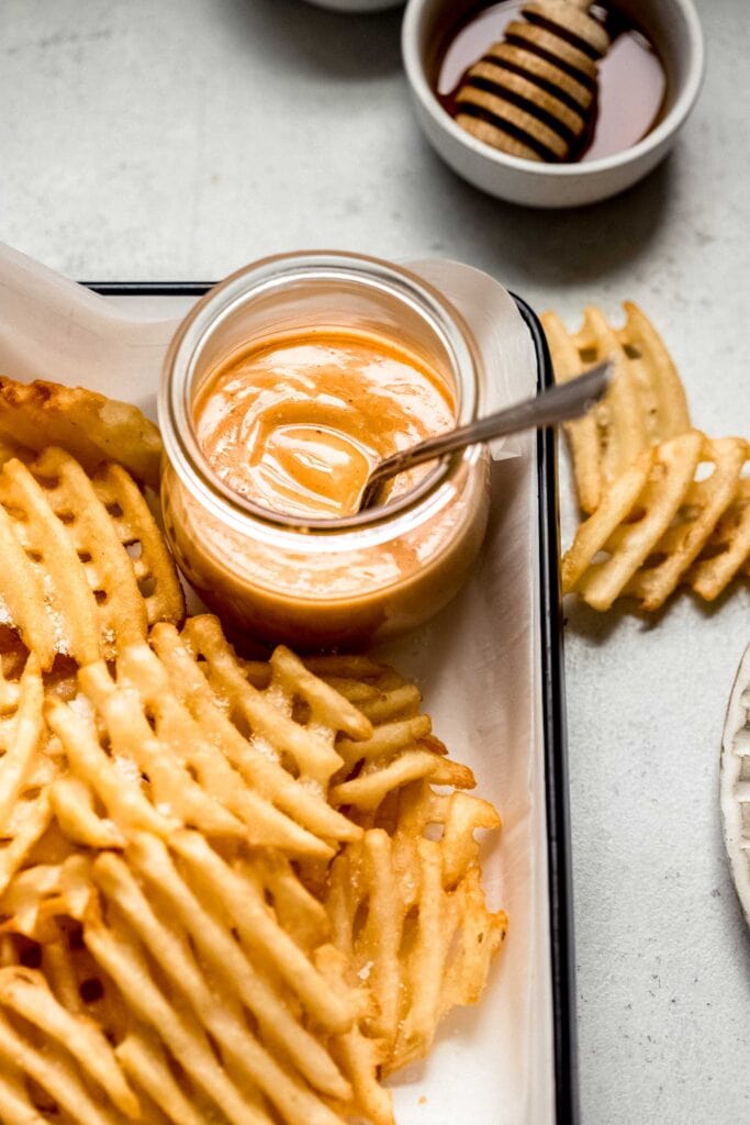 Small jar of chick fil a sauce on tray with waffle fries. 