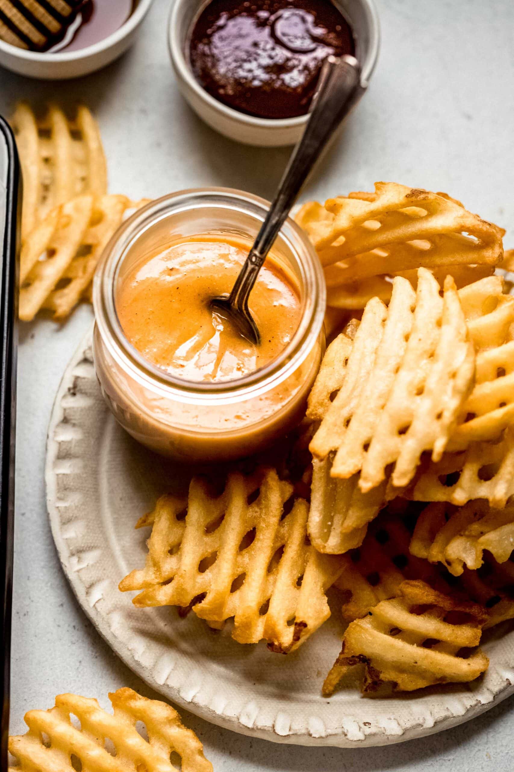 Small jar of chick fil a sauce on plate with waffle fries.