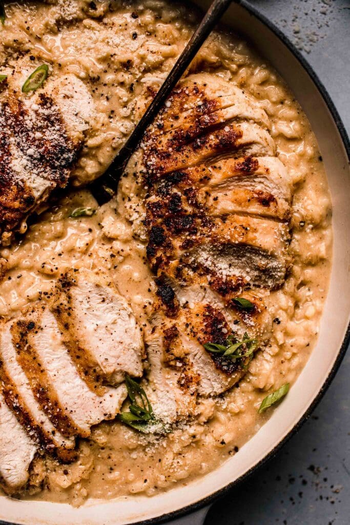 Close up of chicken risotto in skillet with serving spoon. 