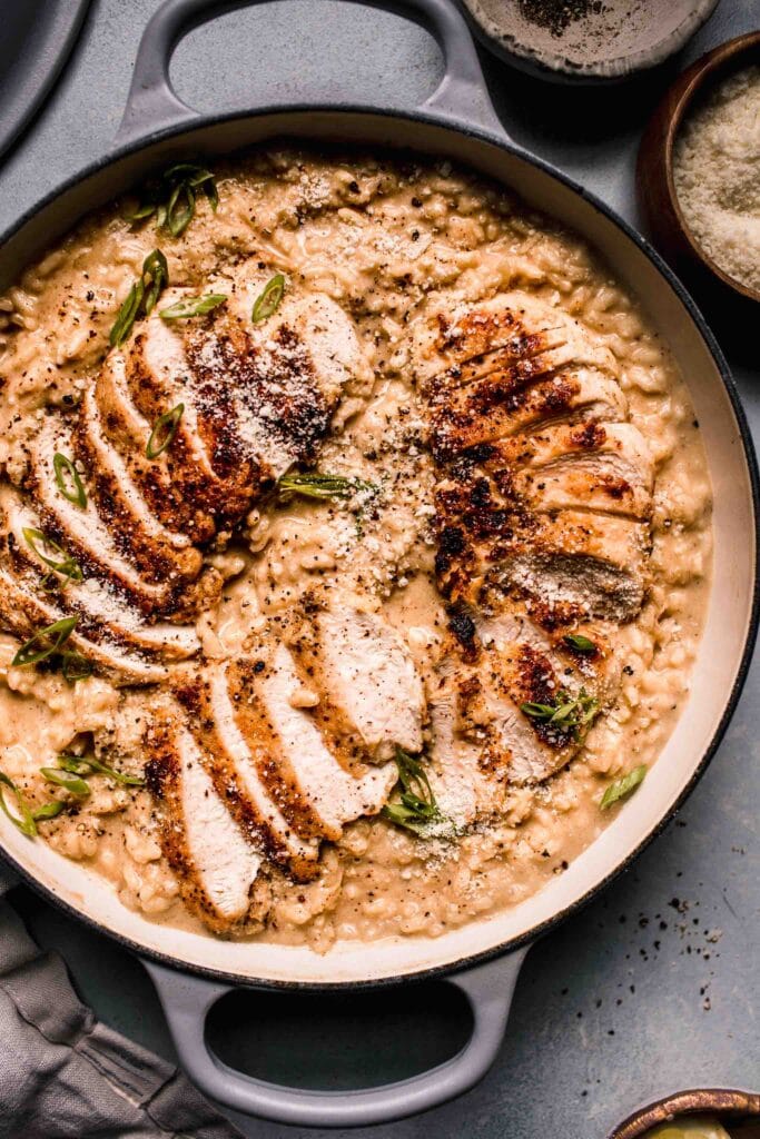 Risotto with sliced chicken breast on top in large skillet. 