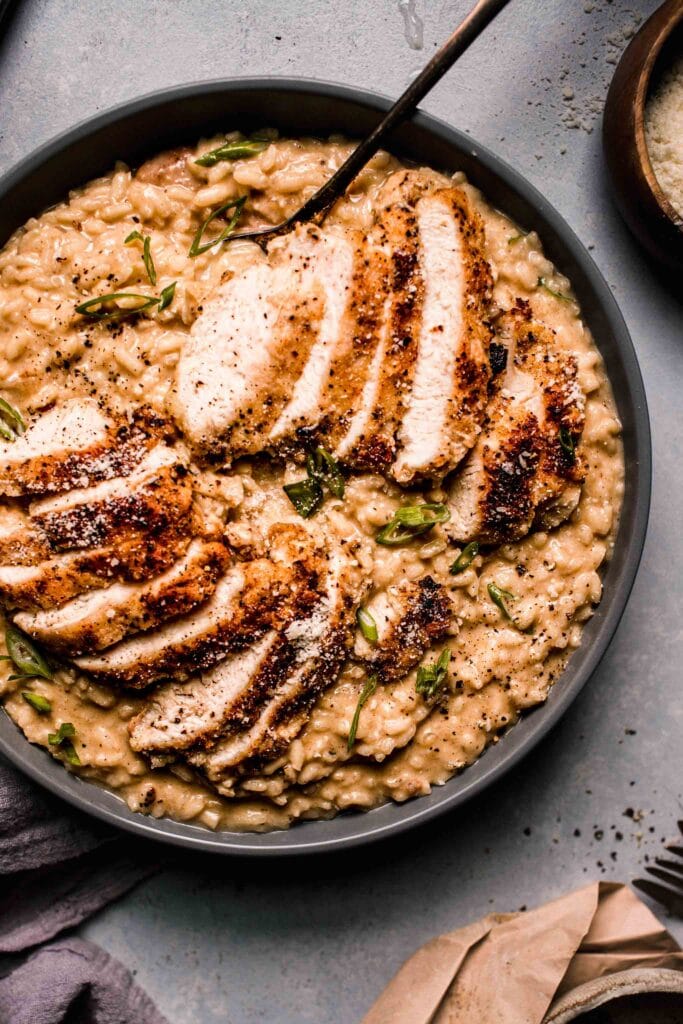 Prepared Chicken risotto in grey serving bowl with spoon.