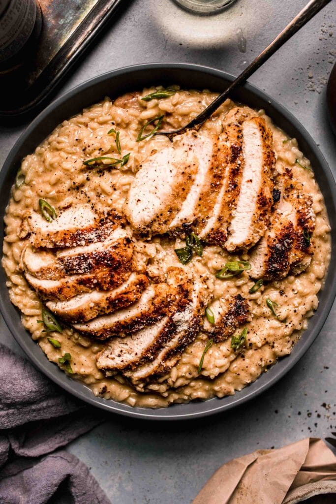 Prepared Chicken risotto in grey serving bowl with spoon.