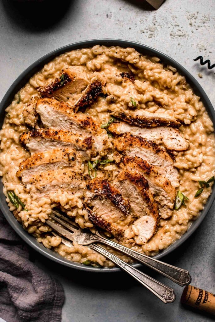 Prepared Chicken risotto in grey serving bowl with spoon.