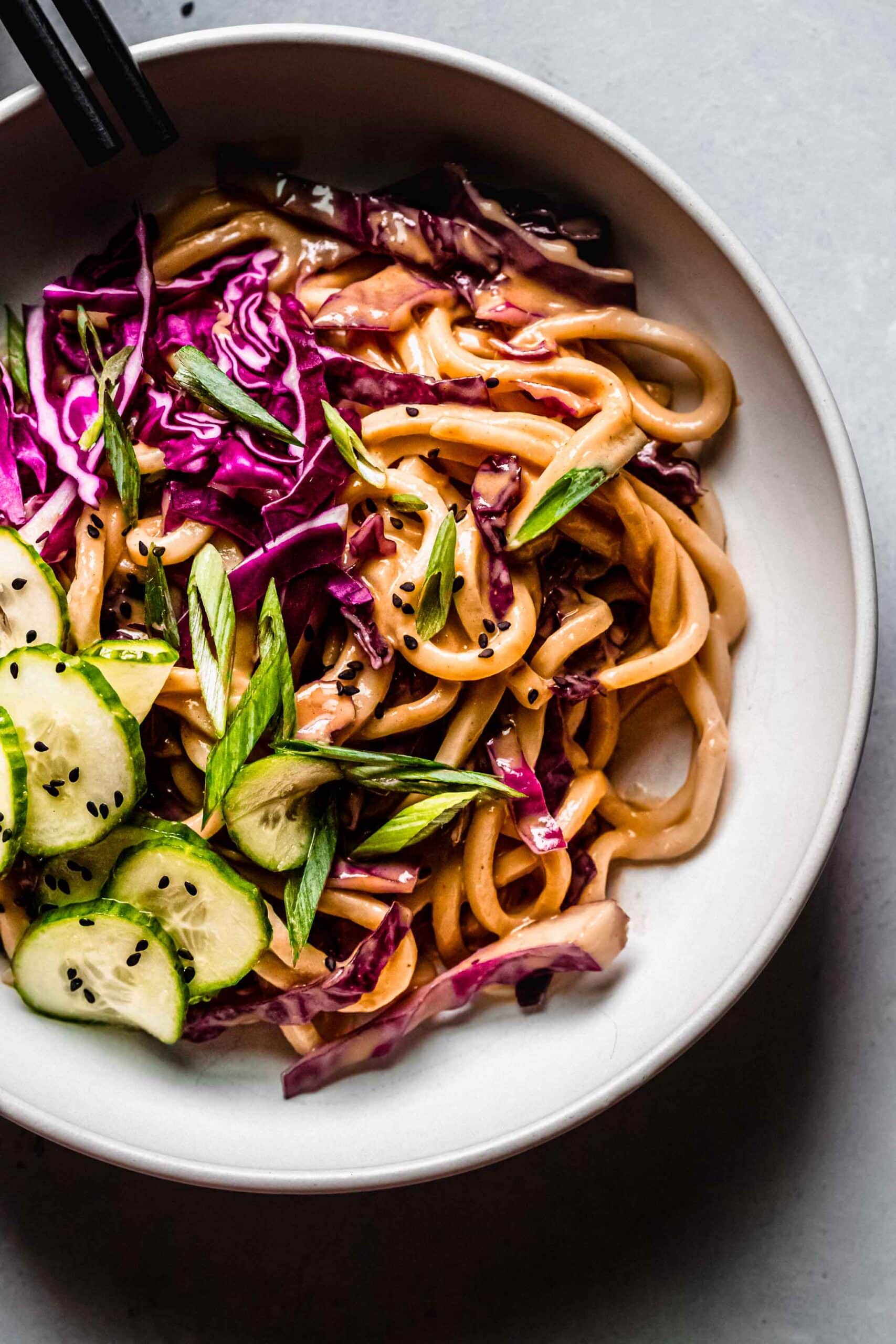 Overhead closeup of cold peanut noodle salad with chopsticks.