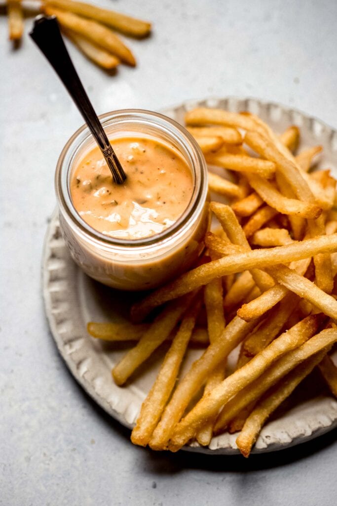 French fries on plate with dipping sauce. 