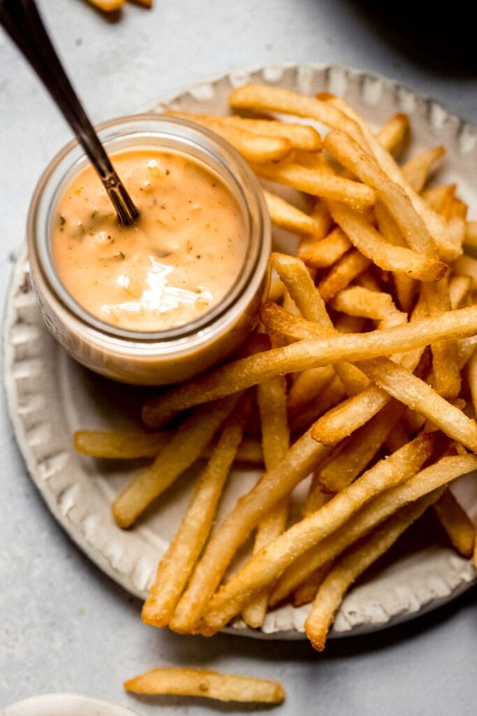 Overhead shot of small bowl of fry sauce next to plate of fries.