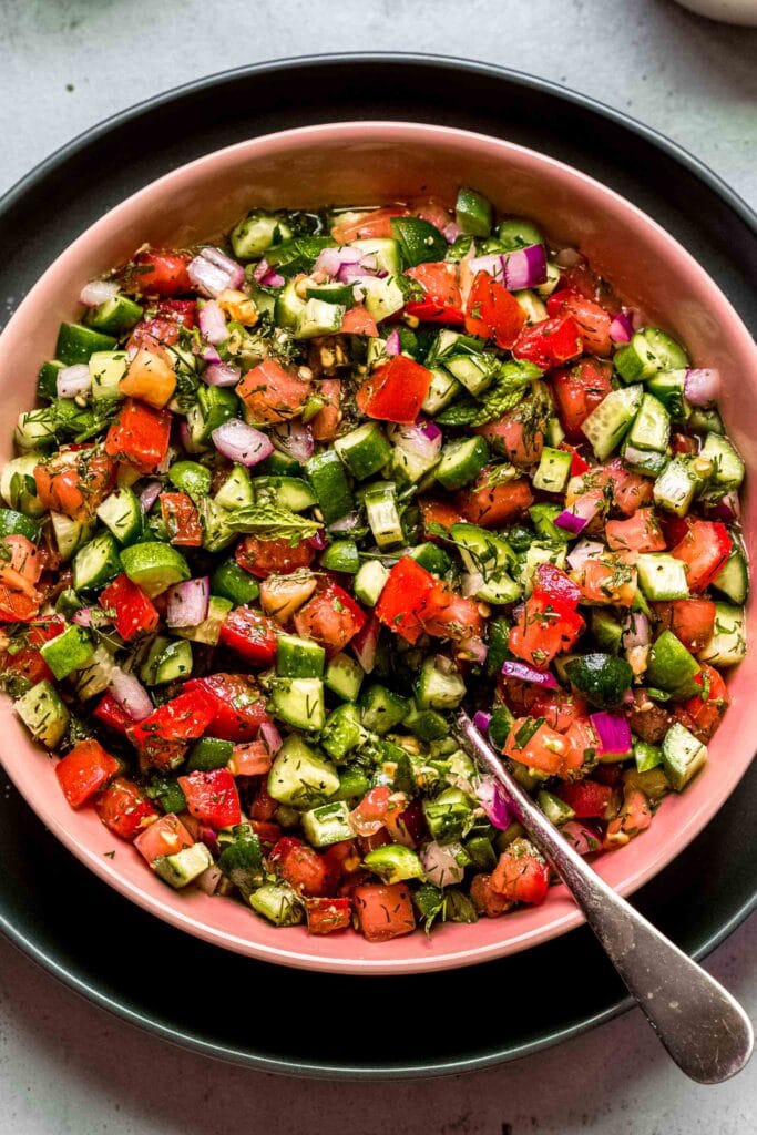 Shirazi salad centered in frame with serving spoon.