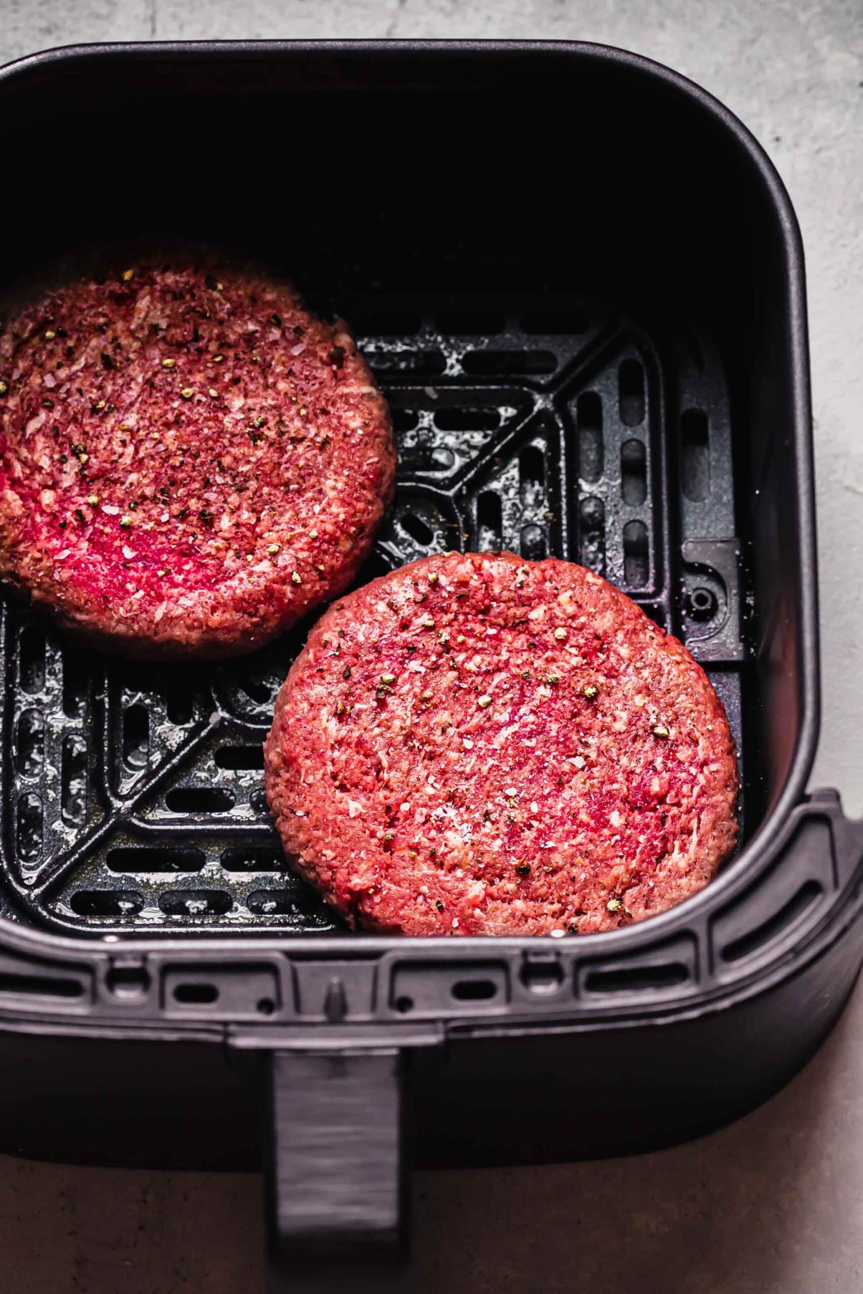 Uncooked burger patties in air fryer.