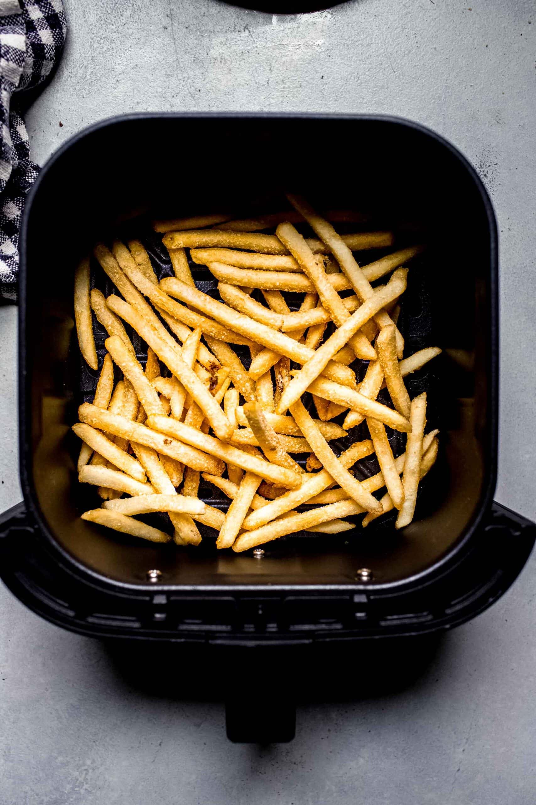 Uncooked fries in air fryer basket. 