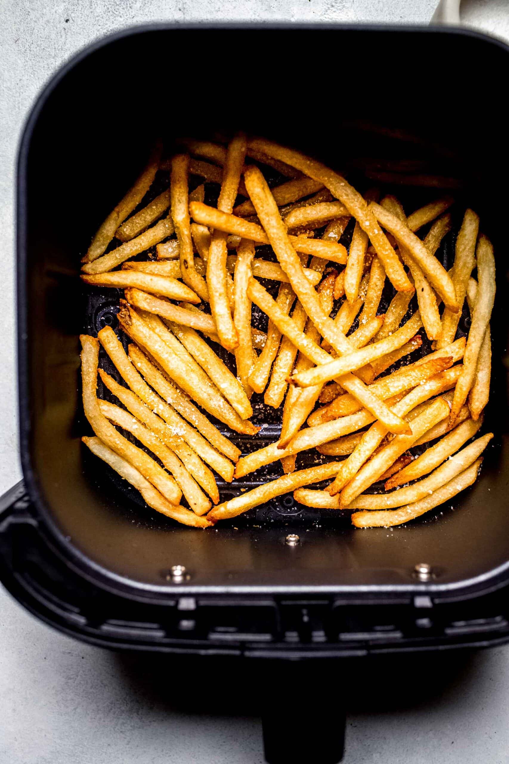 Cooked fries in air fryer basket.