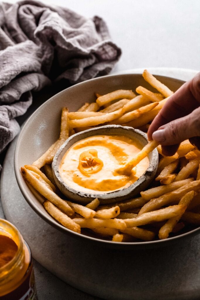 Hand dipping fry into aji sauce. 