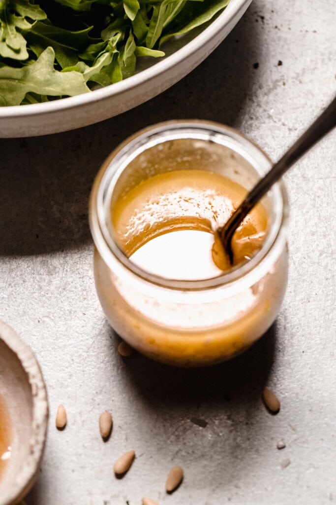 Arugula salad dressing in small jar with spoon.