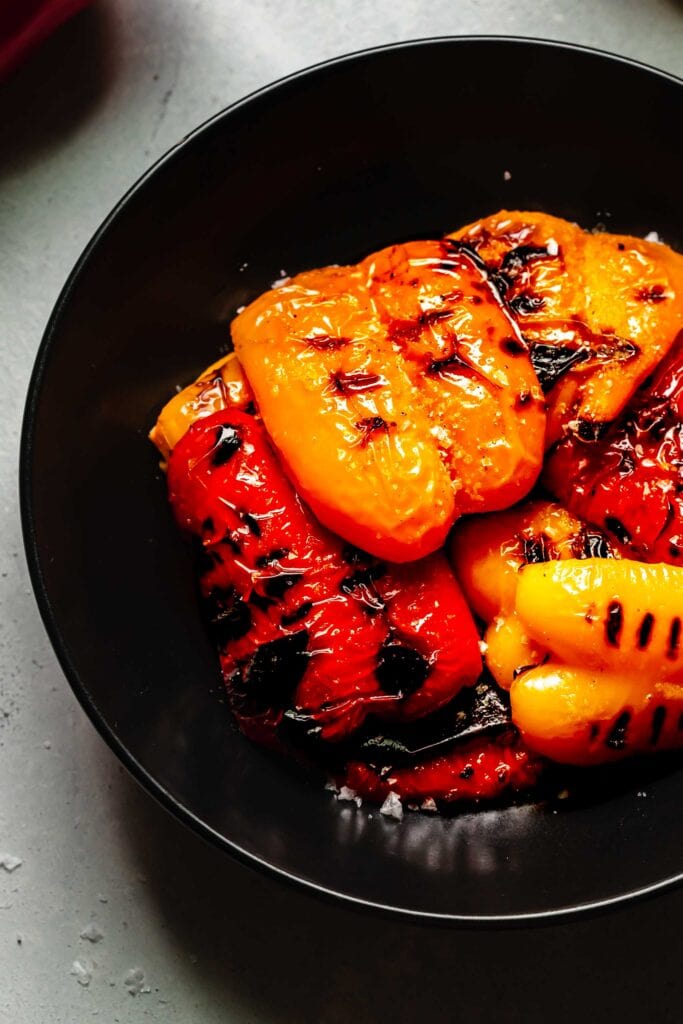 Grilled peppers arranged in shallow black bowl.