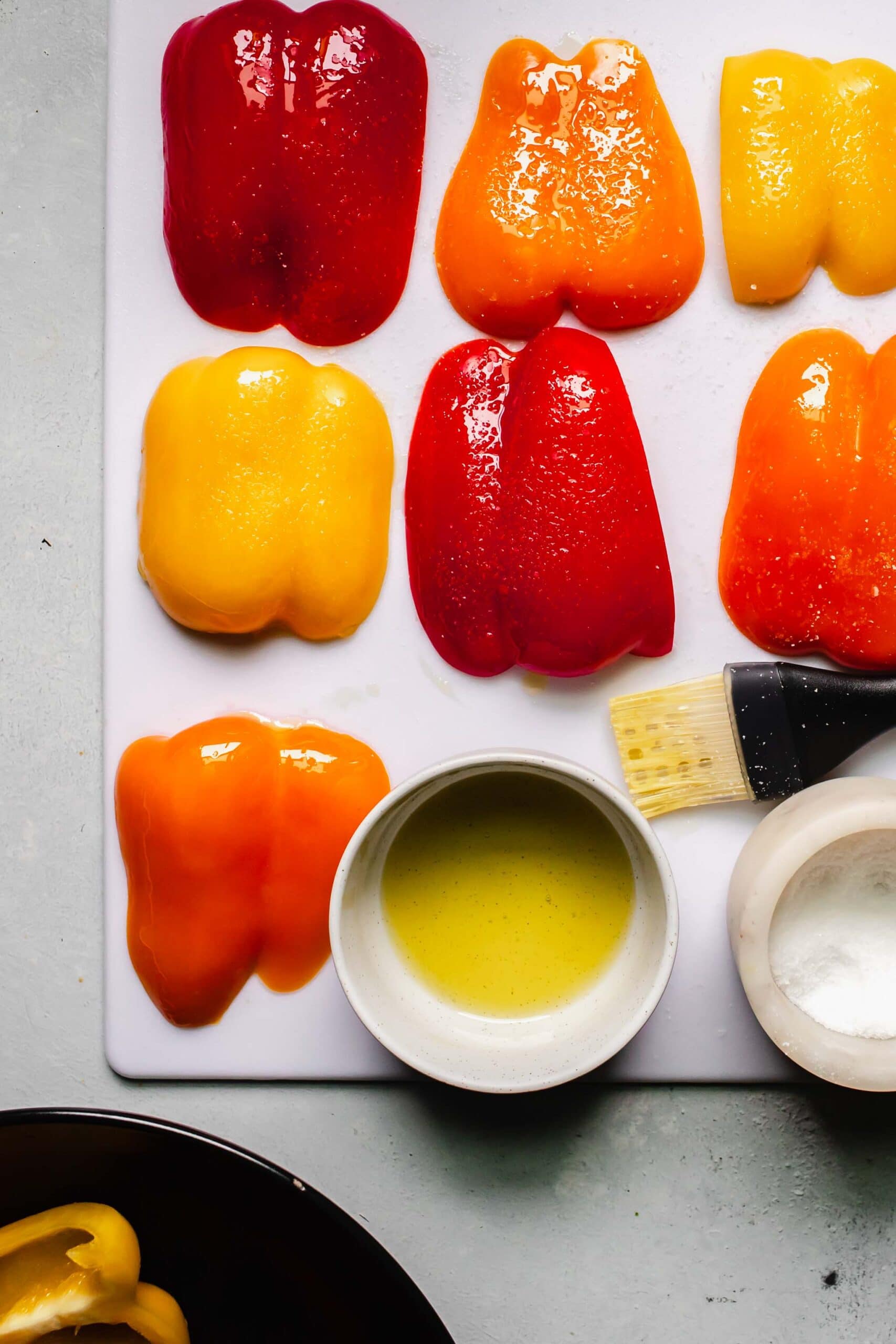 Peppers being brushed with oil and sprinkled with salt.