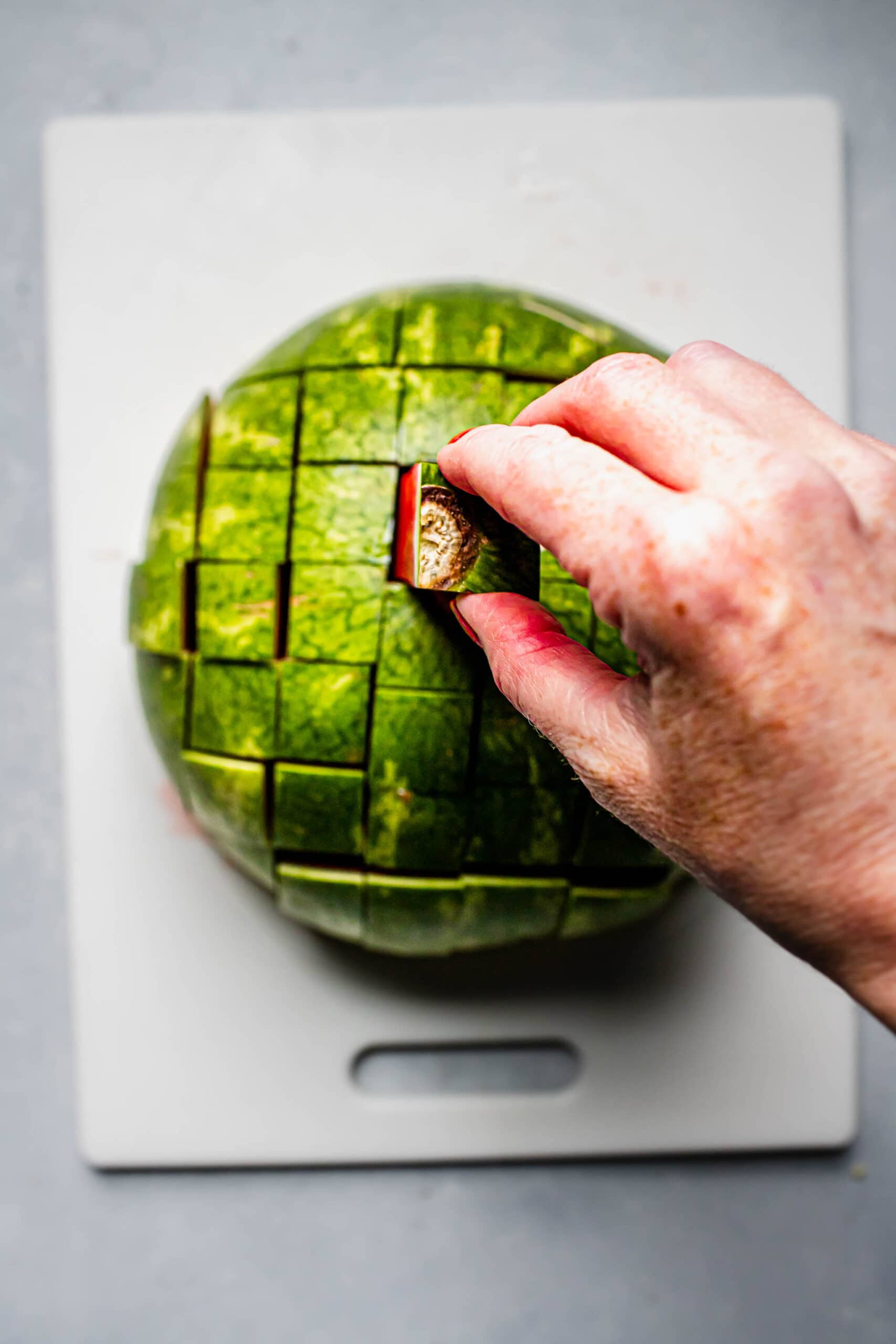 Hand pulling stick of watermelon out. 