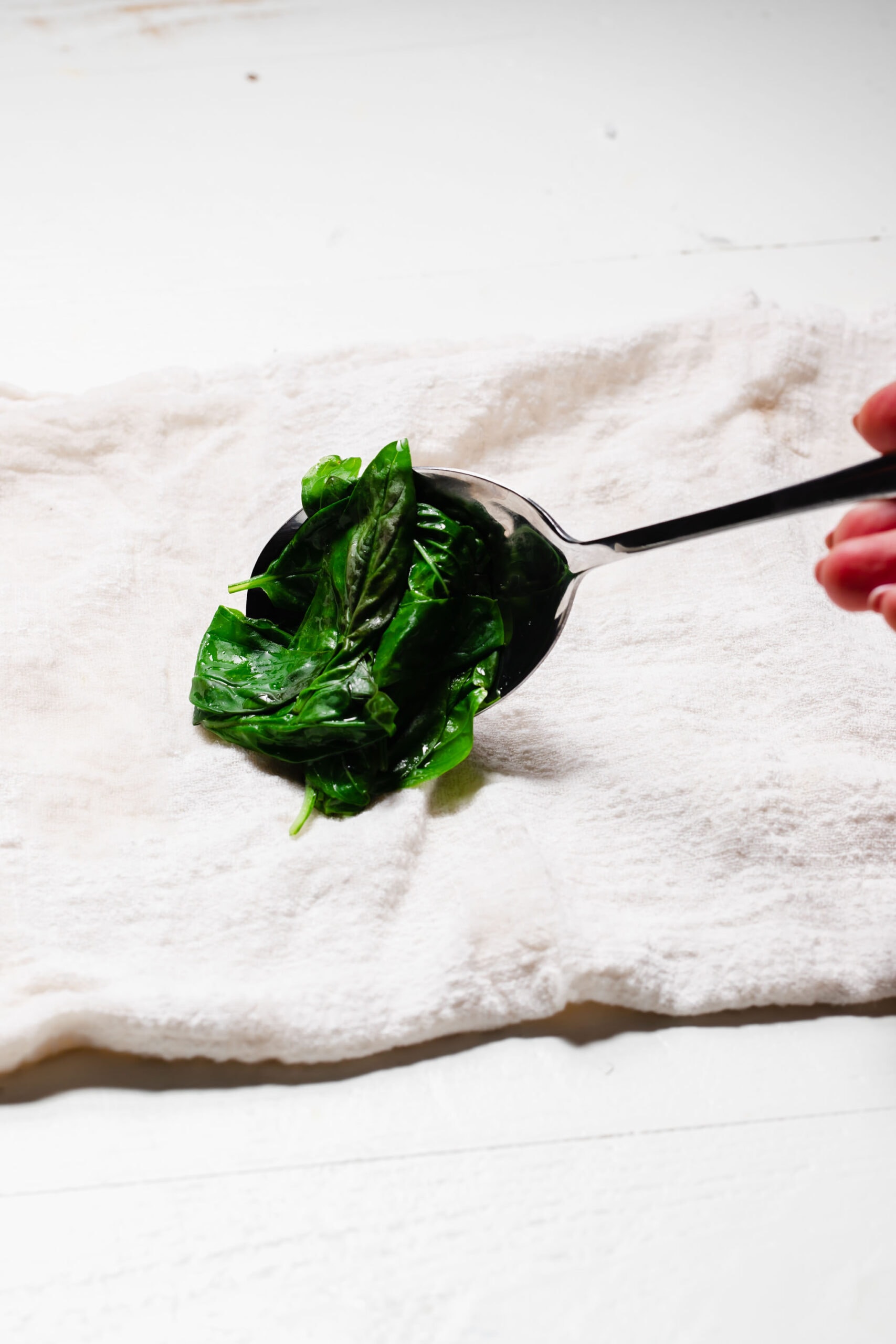 SLOTTED SPOON PLACING BASIL ON TOWEL