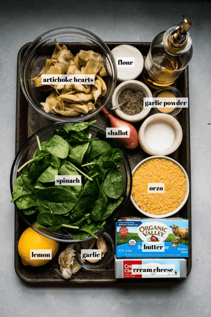 Ingredients for spinach artichoke orzo labeled on tray. 