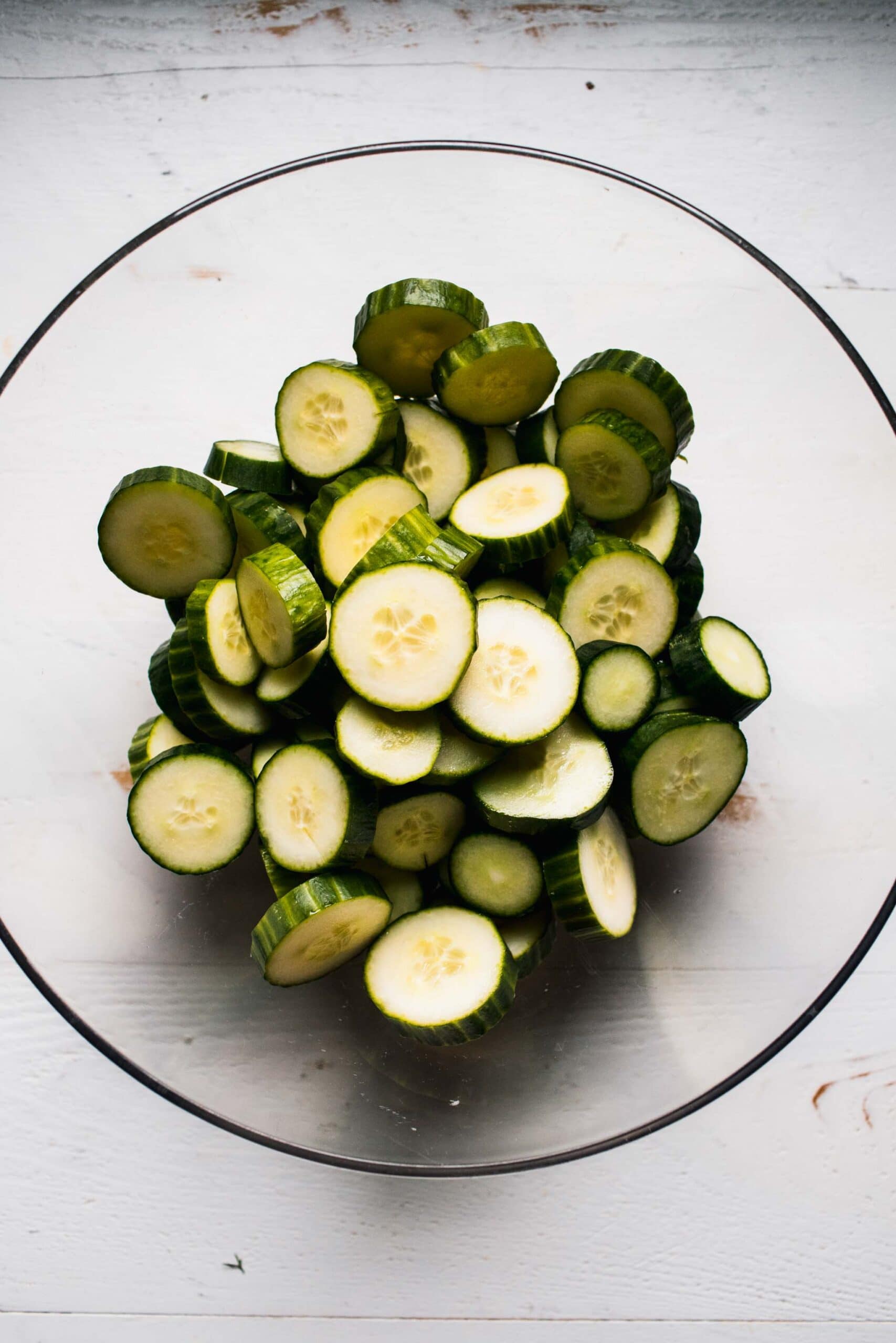 Sliced cucumbers in large bowl.