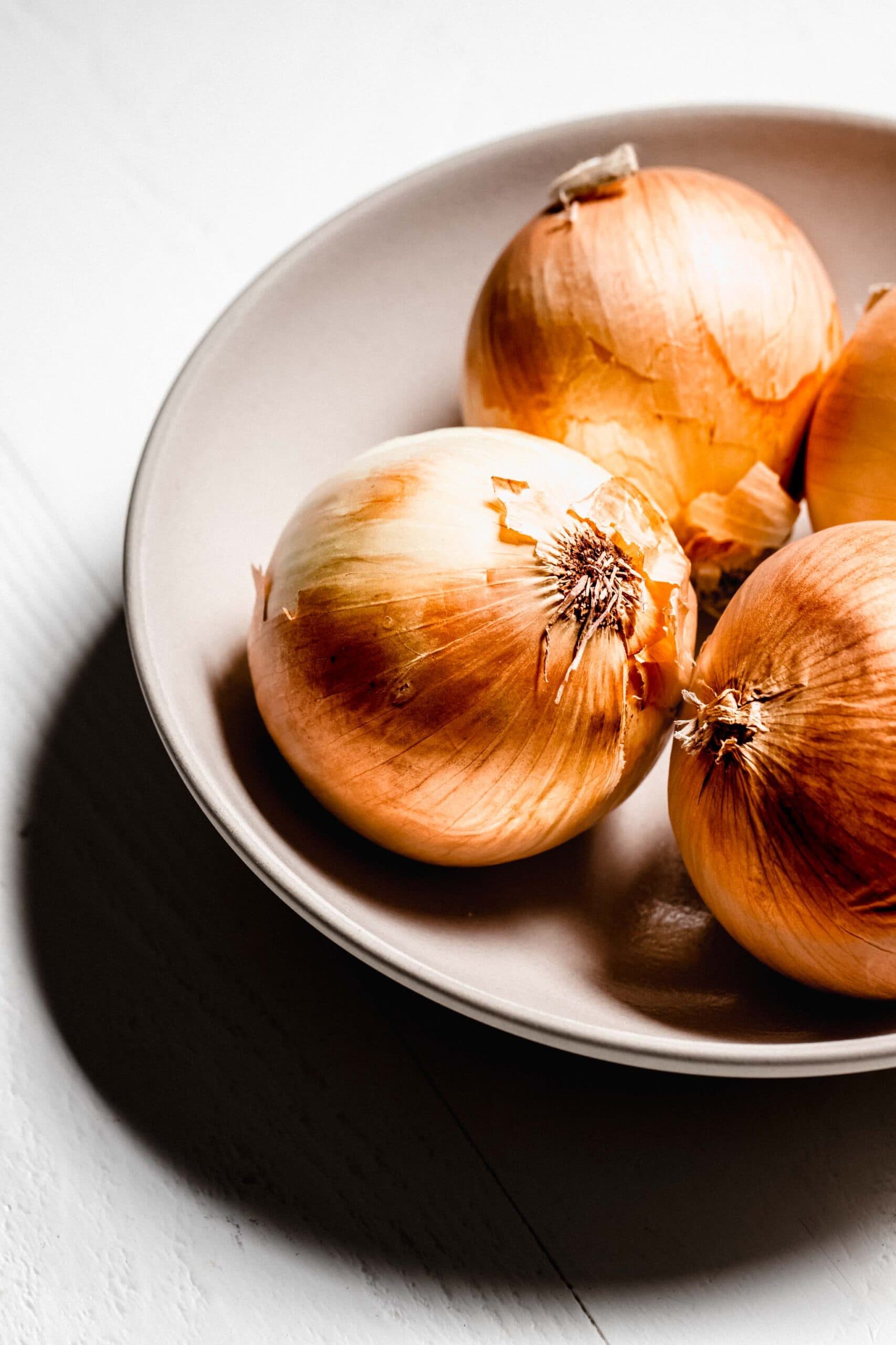 Bowl of whole yellow onions.