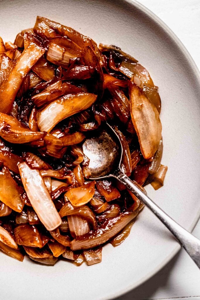 Spoon in bowl of caramelized onions. 