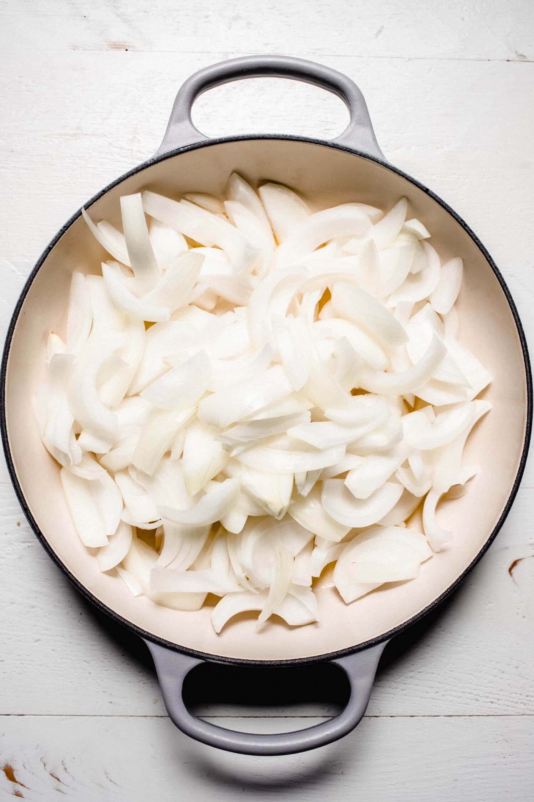 Uncooked sliced onions in skillet. 