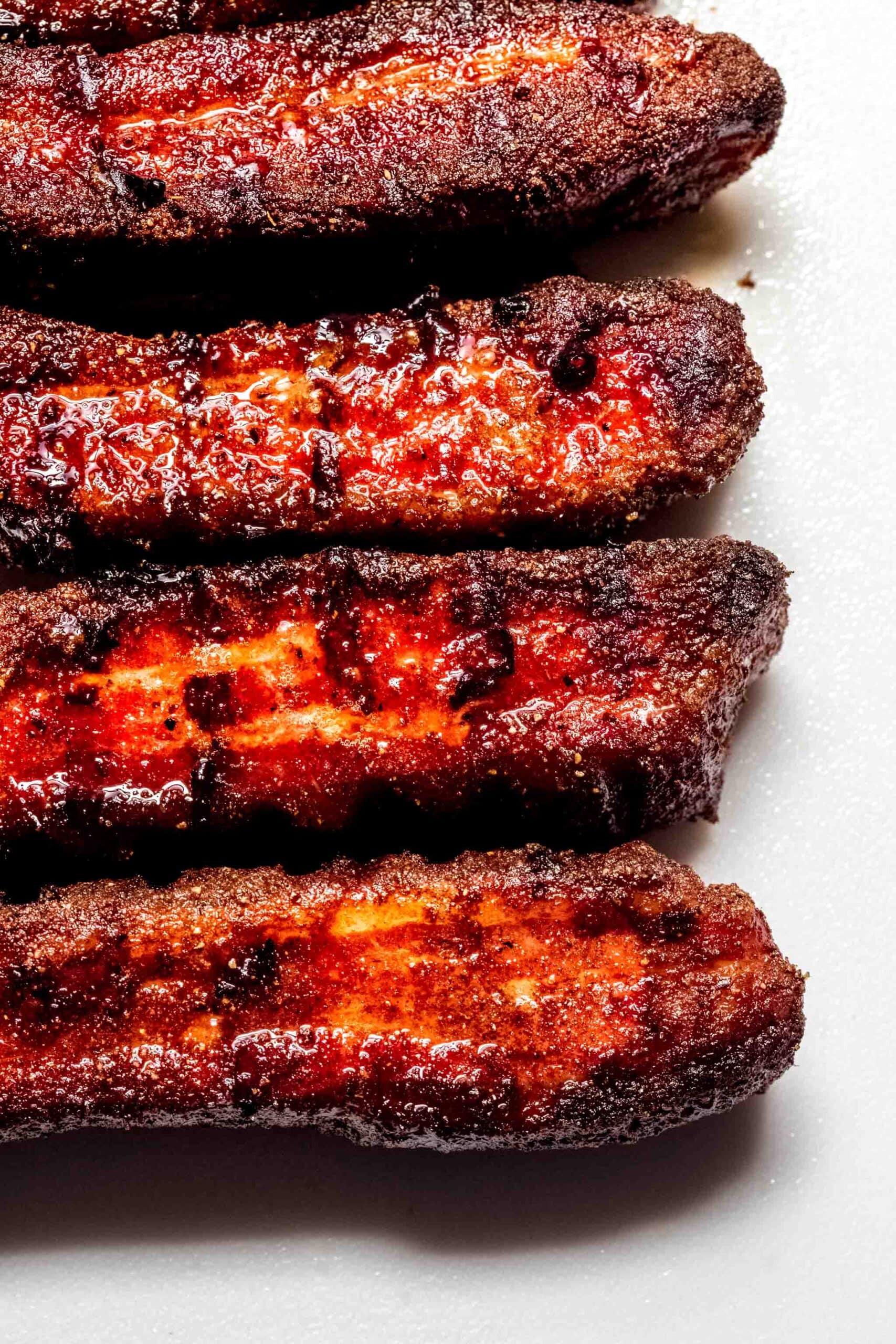 Four pieces of smoked pork belly on white background.