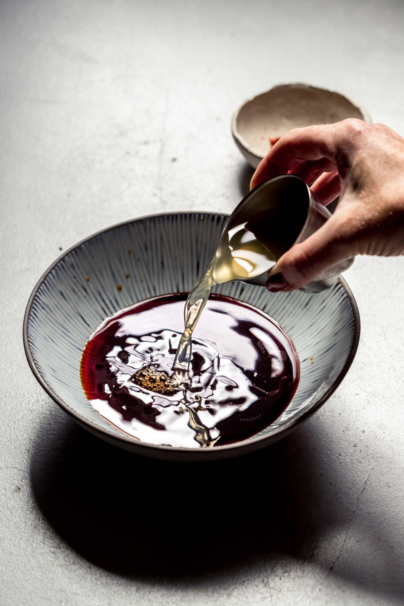 Rice vinegar pouring into bowl.