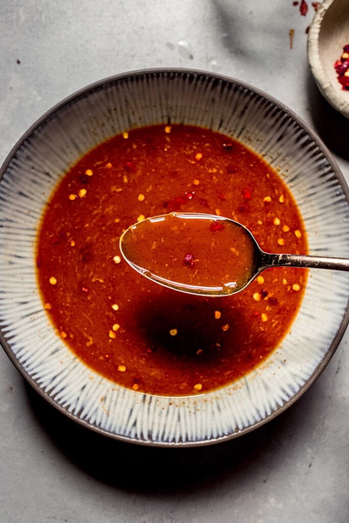 Spoon lifting stir fry sauce out of bowl.