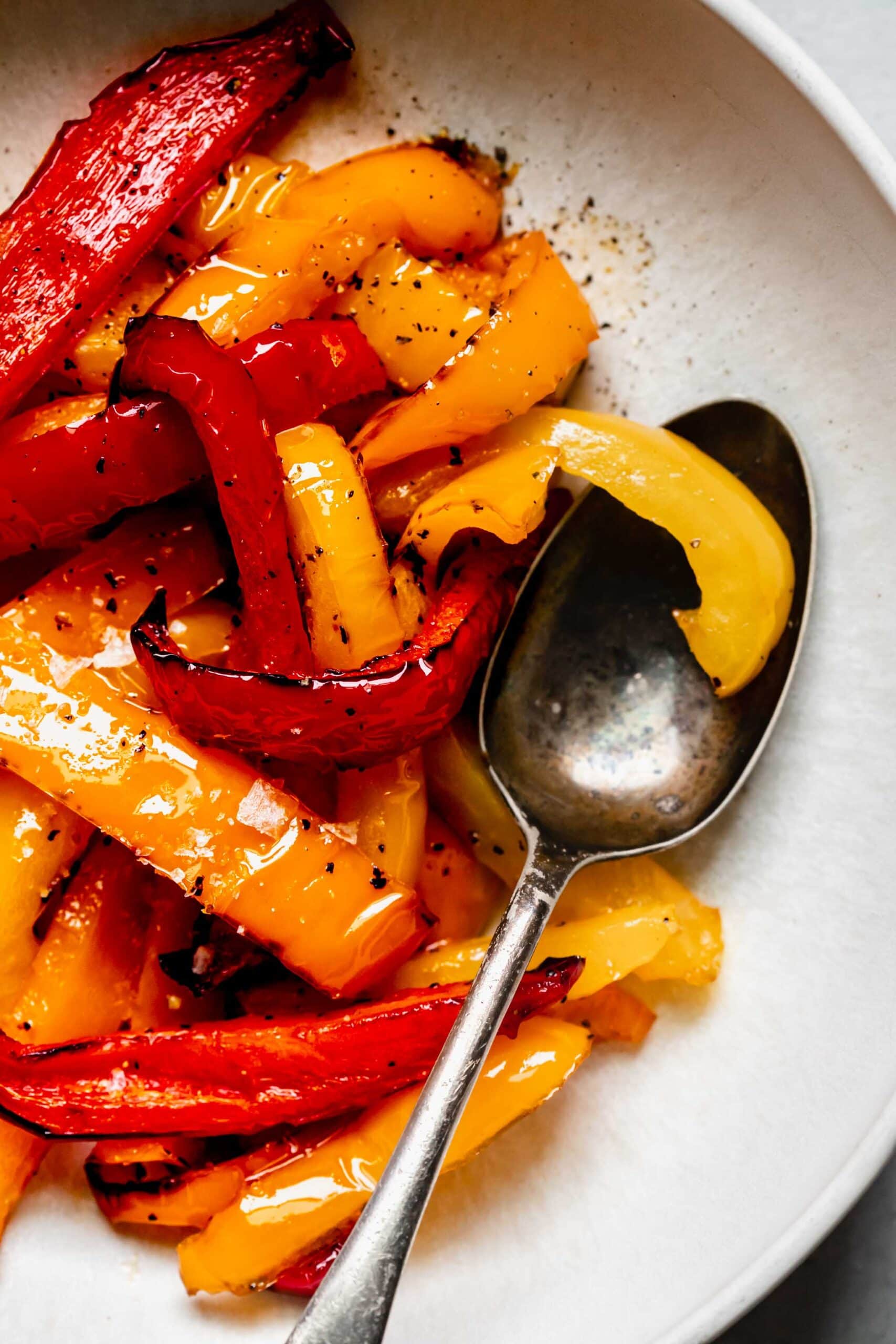 Overhead close up of air fried peppers in white serving bowl with spoon.