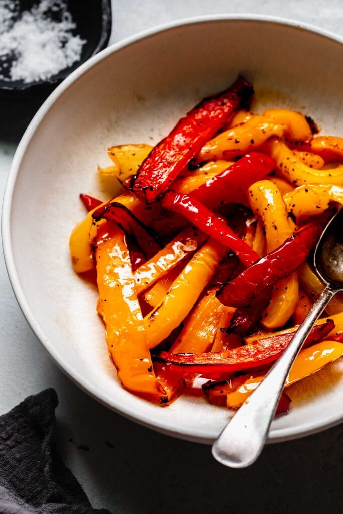 Charred yellow + red peppers in white serving bowl. 