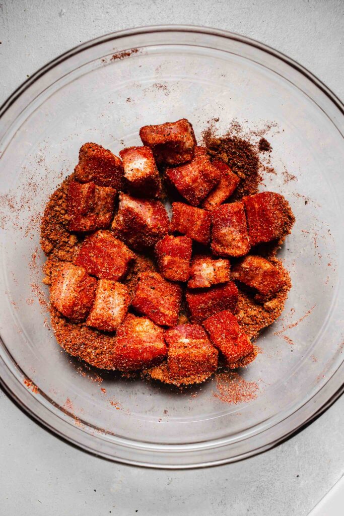 Pork belly cubes being tossed in dry rub. 