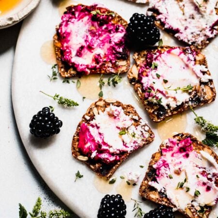 Crackers spread with blackberry goat cheese on serving platter.